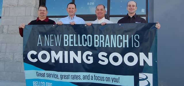 Bellco employees holding a banner to announce a new branch opening