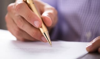 Image of a Person Signing a Form Image of a Person Signing a Form