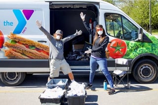 Photo of YMCA workers distributing food in a van Photo of YMCA workers distributing food in a van