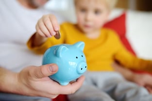 Child Putting Coin in Piggy Bank