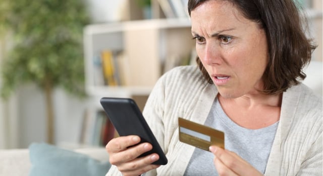 Woman Looking at Phone Holding a Credit Card