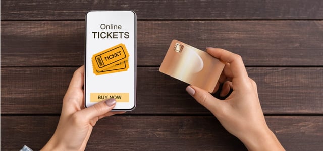 Photo of a woman purchasing tickets on her mobile device with a credit card. Photo of a woman purchasing tickets on her mobile device with a credit card.