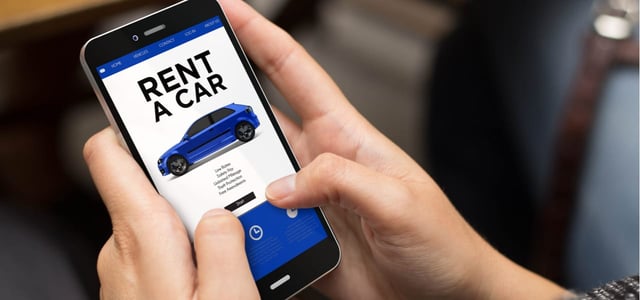 Photo of a man booking a rental vehicle on a phone.