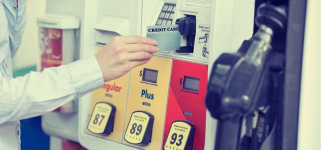 Photo of a woman inserting a credit card to pay at a fuel pump.