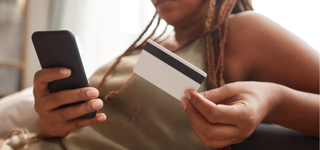 Woman looking at a phone and a credit card.
