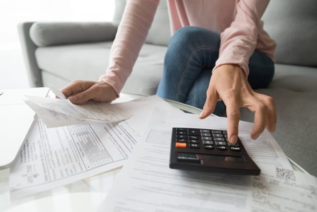 Woman holding paper bills using calculator Woman holding paper bills using calculator