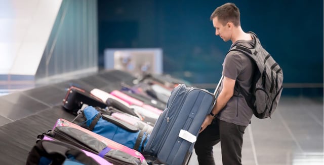 Man collecting his luggage from an airport.