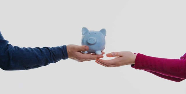 Man handing a blue piggy bank to a woman