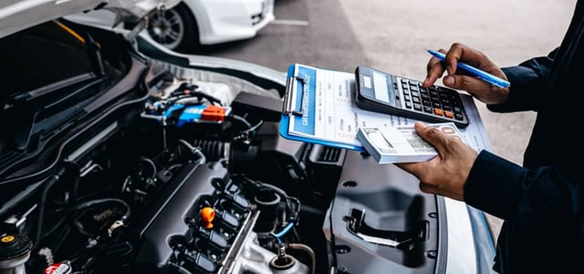 Mechanic calculates the cost of car repairs to customer at garage workshop Mechanic calculates the cost of car repairs to customer at garage workshop