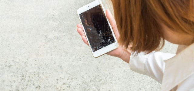Woman picking broken smart phone up from the floor