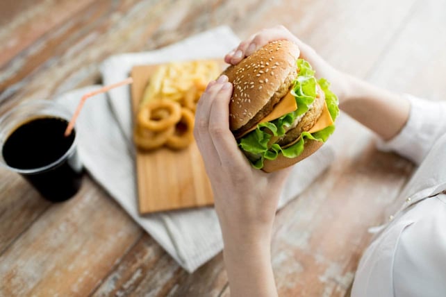 fast food, close up of woman hands holding hamburger or cheeseburger