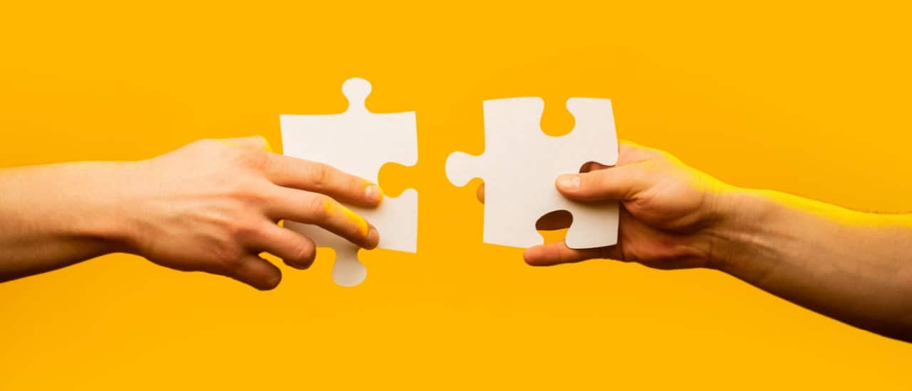 Yellow Background, Two Hands Joining Puzzle Pieces
