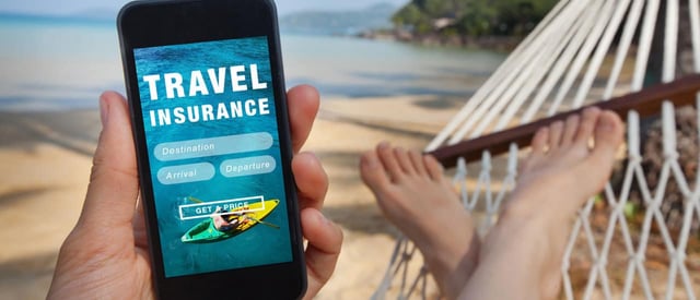 A man on a hammock at a beach holding a phone with the words travel insurance on it