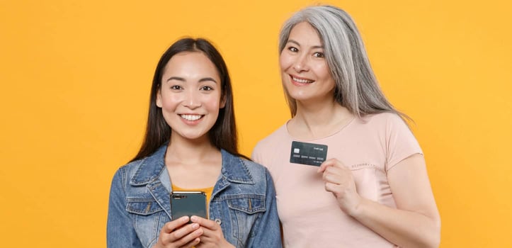 Two women, one holding a phone, the other a credit card, authorized user concept