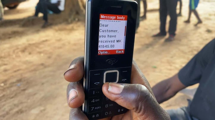 Recipient receiving universal basic income transfer via mobile phone