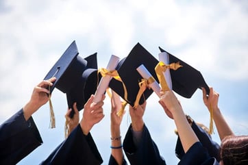 hands holding up graduation caps hands holding up graduation caps